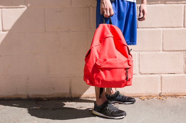 Photo gratuit adolescent avec sac à dos rouge dans la rue