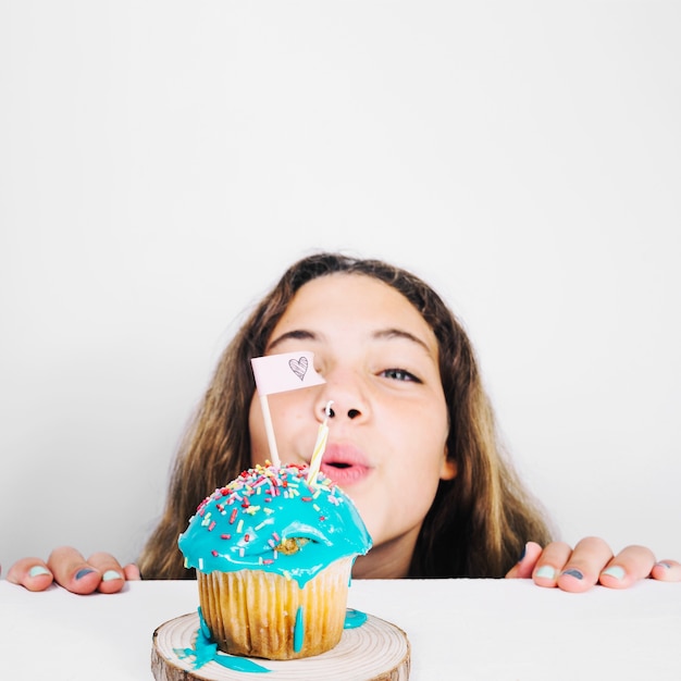 Photo gratuite adolescent soufflant la bougie sur cupcake