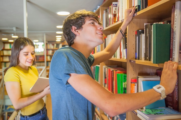 Adolescent souriant, choisir un livre près de la petite amie