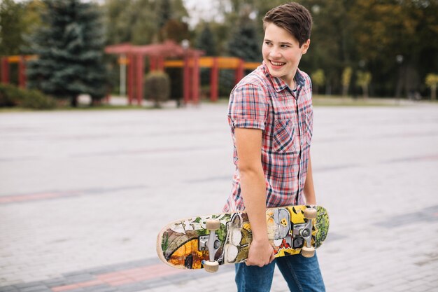 Adolescent souriant avec planche à roulettes