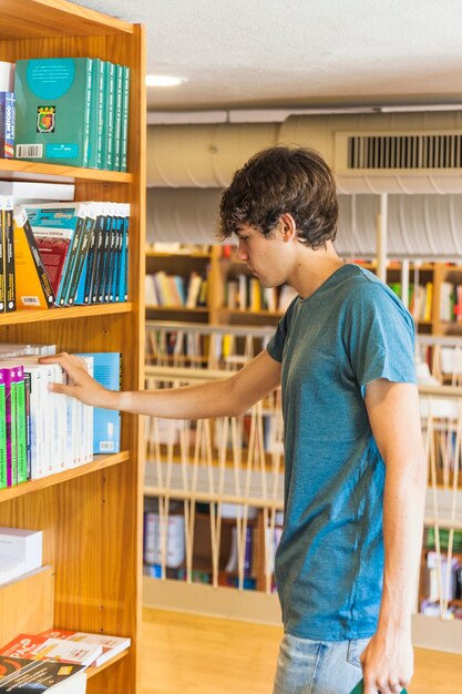 Adolescent, toucher des livres sur une étagère