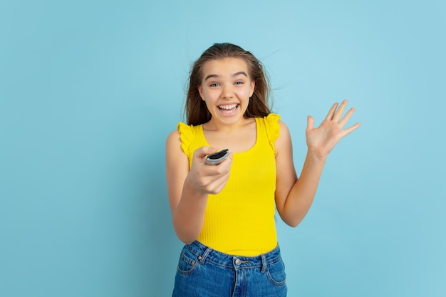 Adolescente à l'aide de la télécommande du téléviseur