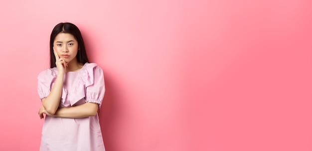 Photo gratuite une adolescente asiatique ennuyée a l'air indifférente à l'appareil photo face maigre à portée de main dans une pose sceptique debout réticente