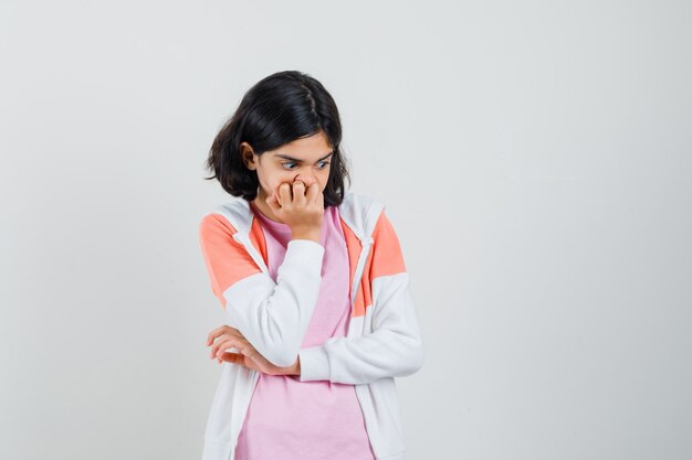 Adolescente en attente de quelque chose en veste, chemise rose et à la recherche excitée.