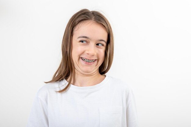 Une adolescente drôle avec un appareil orthopédique rit sur un fond blanc.