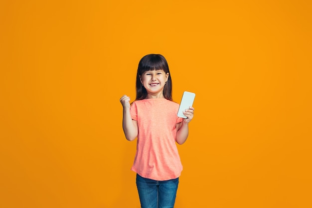 L'adolescente heureuse debout et souriant contre l'orange.