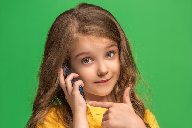 L'adolescente heureuse debout et souriant sur fond vert.