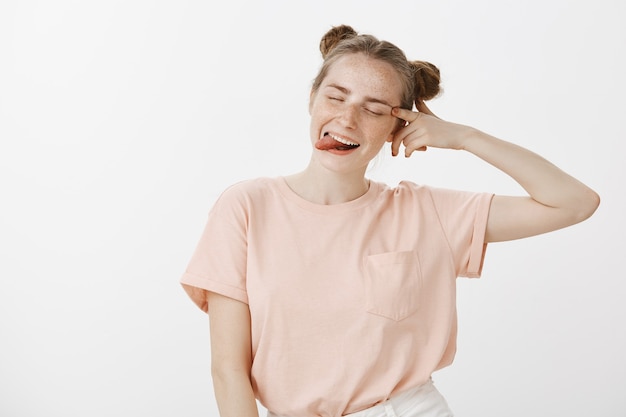 Adolescente impertinente et insouciante posant contre le mur blanc