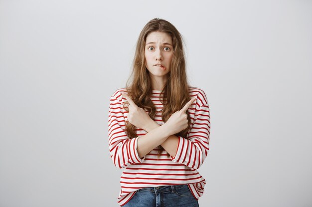 Adolescente indécise et perplexe, pointant du doigt sur le côté, je ne sais pas quoi choisir