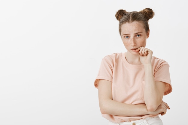 Photo gratuite adolescente indécise posant contre le mur blanc