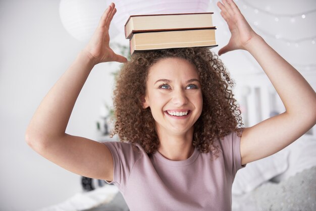 Adolescente avec des livres sur la tête