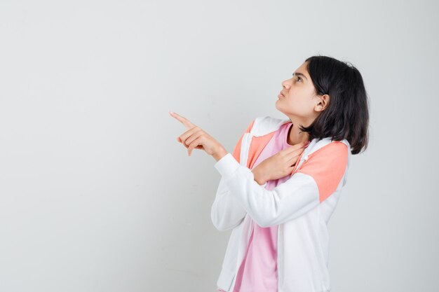 Adolescente montrant quelqu'un en veste, chemise rose et à la dégoûté.