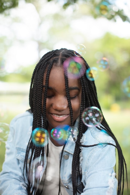 Photo gratuite adolescente noire mignonne jouant avec des bulles de savon