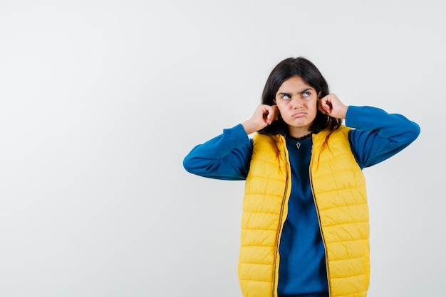 L'adolescente pensante tire ses oreilles sur fond blanc