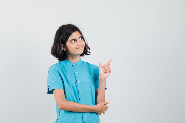 Adolescente pointant vers l'extérieur en chemise bleue et à la satisfaction.