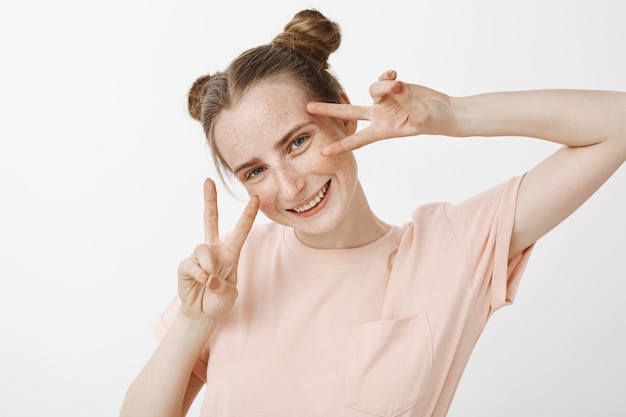 Adolescente rousse belle stupide et heureuse posant contre le mur blanc