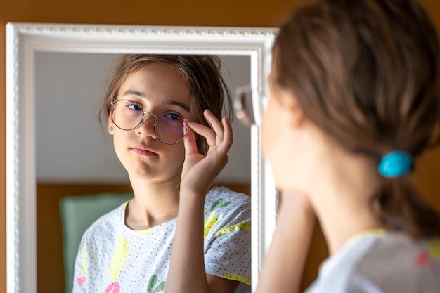 Photo gratuite une adolescente se regarde dans le miroir le matin