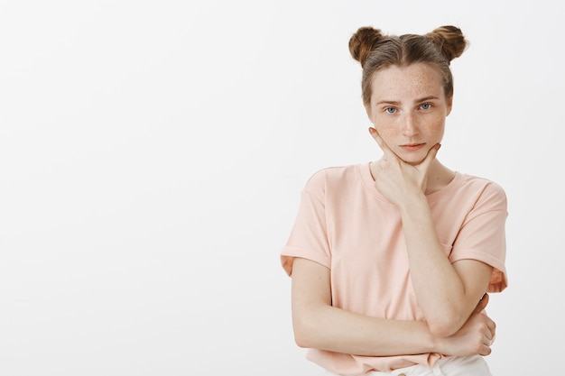 Adolescente sérieuse posant contre le mur blanc