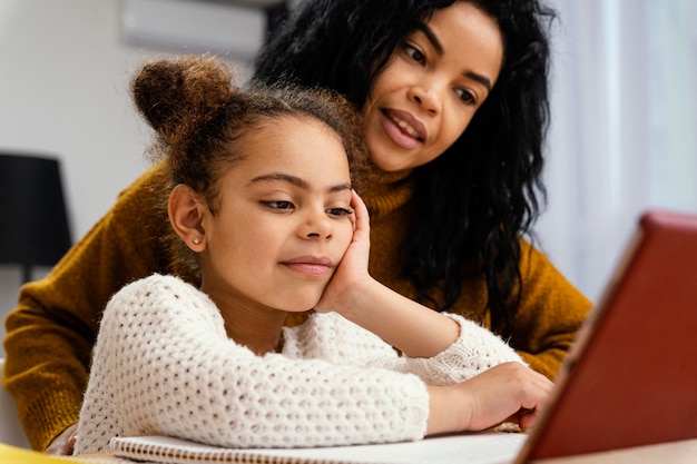 Adolescente Smiley aidant la petite soeur pendant l'école en ligne avec tablette