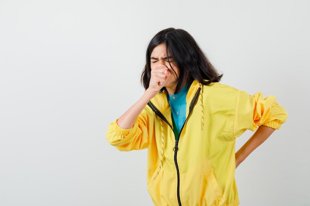 Une adolescente souffrant de toux en veste jaune et ayant l'air malade. vue de face.