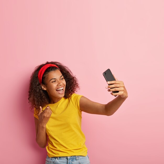 Adolescente souriante aux cheveux bouclés posant en tshirt jaune