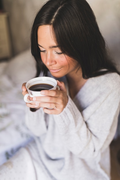 Adolescente souriante buvant du café dans une tasse