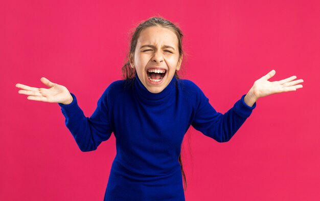 Adolescente stressée montrant les mains vides criant les yeux fermés isolée sur le mur rose