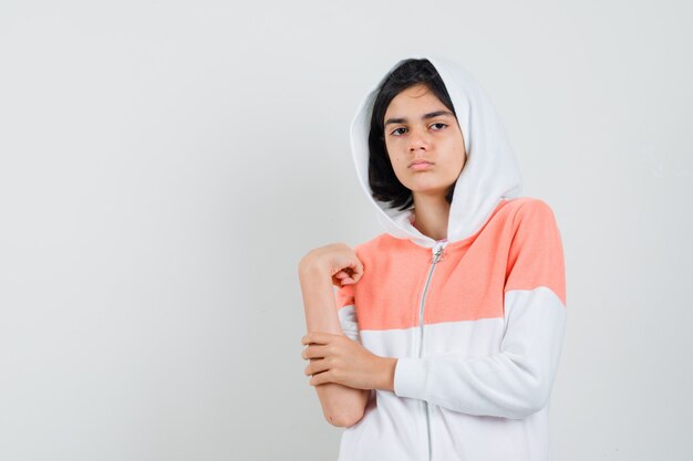 Adolescente en sweat-shirt tenant son bras et à la recherche de sérieux.