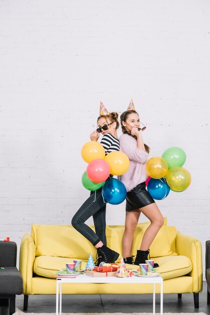 Adolescentes debout dos à dos, tenant des ballons à la main sur la fête