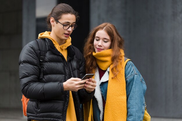 Adolescents attrayants vérifiant un téléphone mobile
