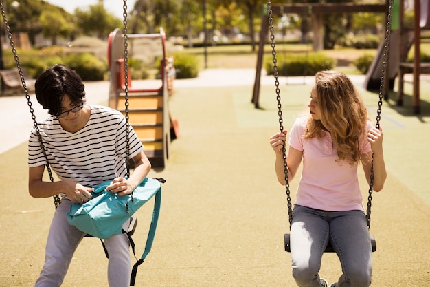 Adolescents multiethniques assis sur des balançoires