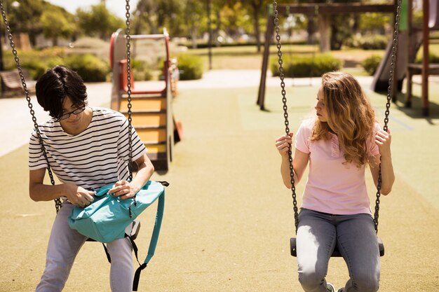 Adolescents multiethniques assis sur des balançoires