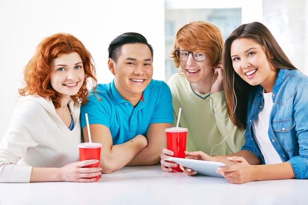 Les adolescents rire avec une tablette et des boissons