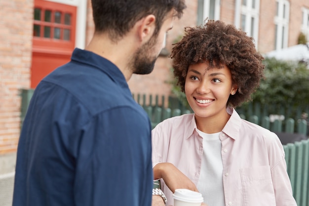 Les adolescents en vêtements décontractés se promènent en zone rurale. Joyful darrk skinned grl a large sourire, regarde l'homme barbu,