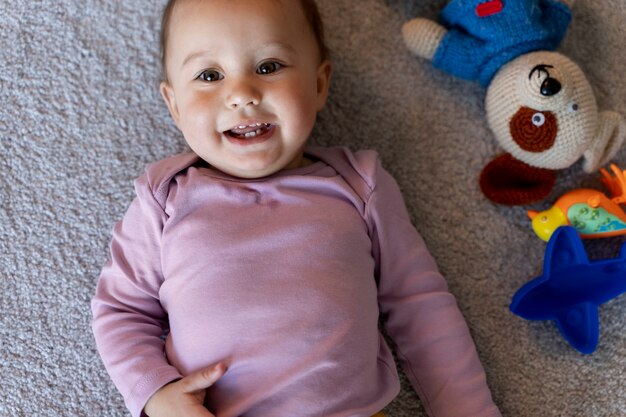 Adorable bébé allongé sur le sol avec des jouets à côté de lui