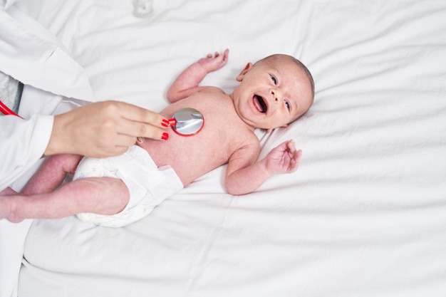 Photo gratuite adorable bébé caucasien ayant un examen cardiaque avec un stéthoscope pleurant dans la chambre