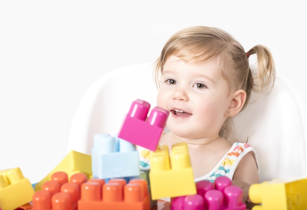 Adorable bébé jouant avec des jouets colorés sur un fond isolé