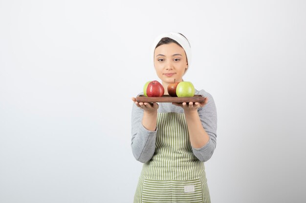 adorable cuisinière tenant une assiette de pommes sur blanc.