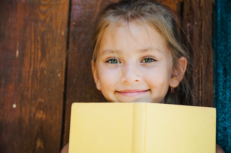 Photo gratuit adorable enfant posant avec un livre