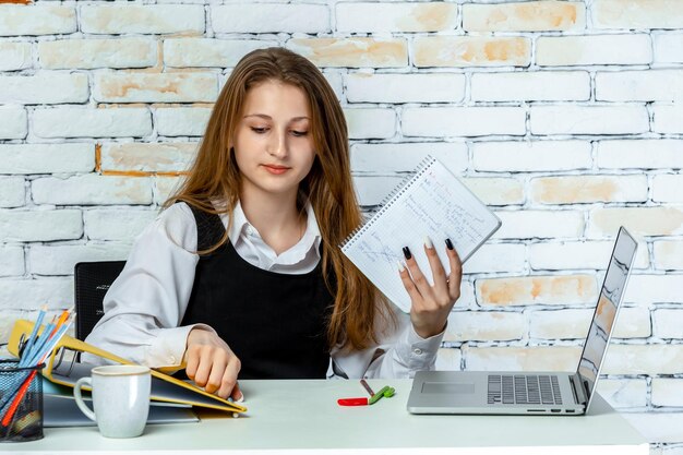 Un adorable étudiant assis derrière le bureau et travaillant Photo de haute qualité