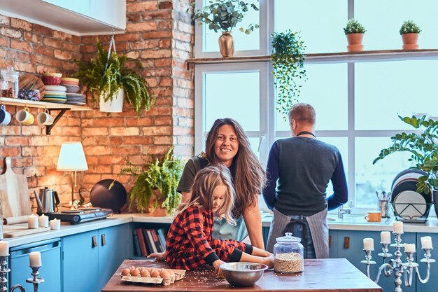 Adorable famille préparant ensemble le petit-déjeuner dans une cuisine de style loft.