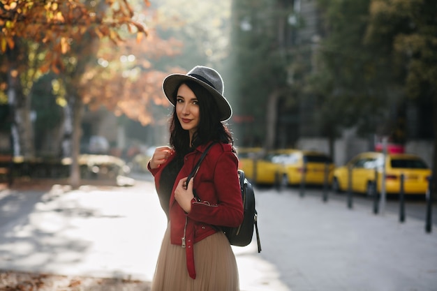 Adorable femme brune avec sac à dos, passer du temps en plein air en journée ensoleillée