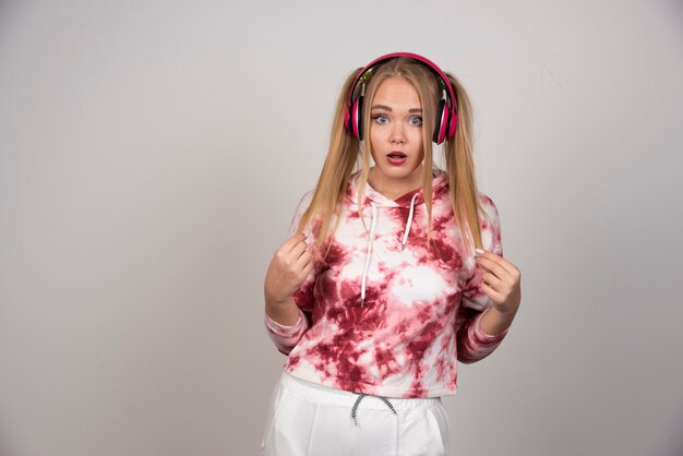 Adorable femme en pull rose debout sur fond gris.