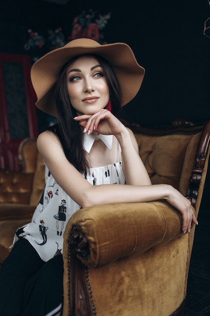 Adorable femme souriante ressemble à une dame assise dans une chaise douce