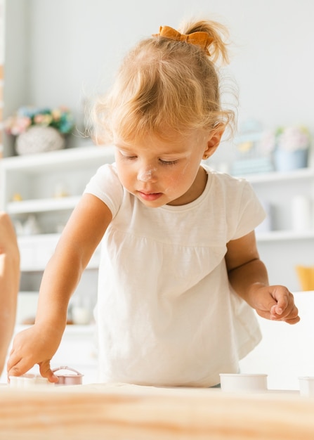 Adorable fille blonde couper la pâte pour les cookies