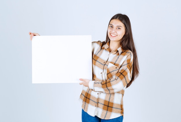 adorable fille avec un grand blanc blanc debout sur un mur blanc.