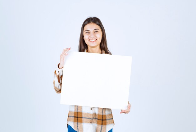 adorable fille avec un grand blanc blanc posant sur un mur blanc.