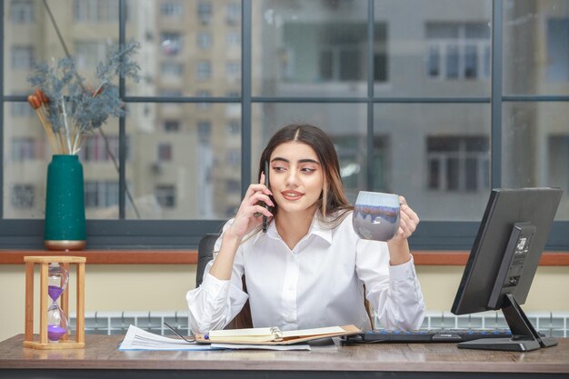 Adorable fille parlant au téléphone et tenant une tasse de thé