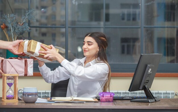 Adorable fille prenant une boîte cadeau au bureau Cadeau d'anniversaire Photo de haute qualité