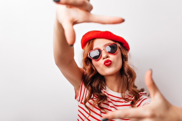 Adorable fille avec rouge à lèvres posant. Dame française glamour en béret faisant l'expression du visage de baiser.